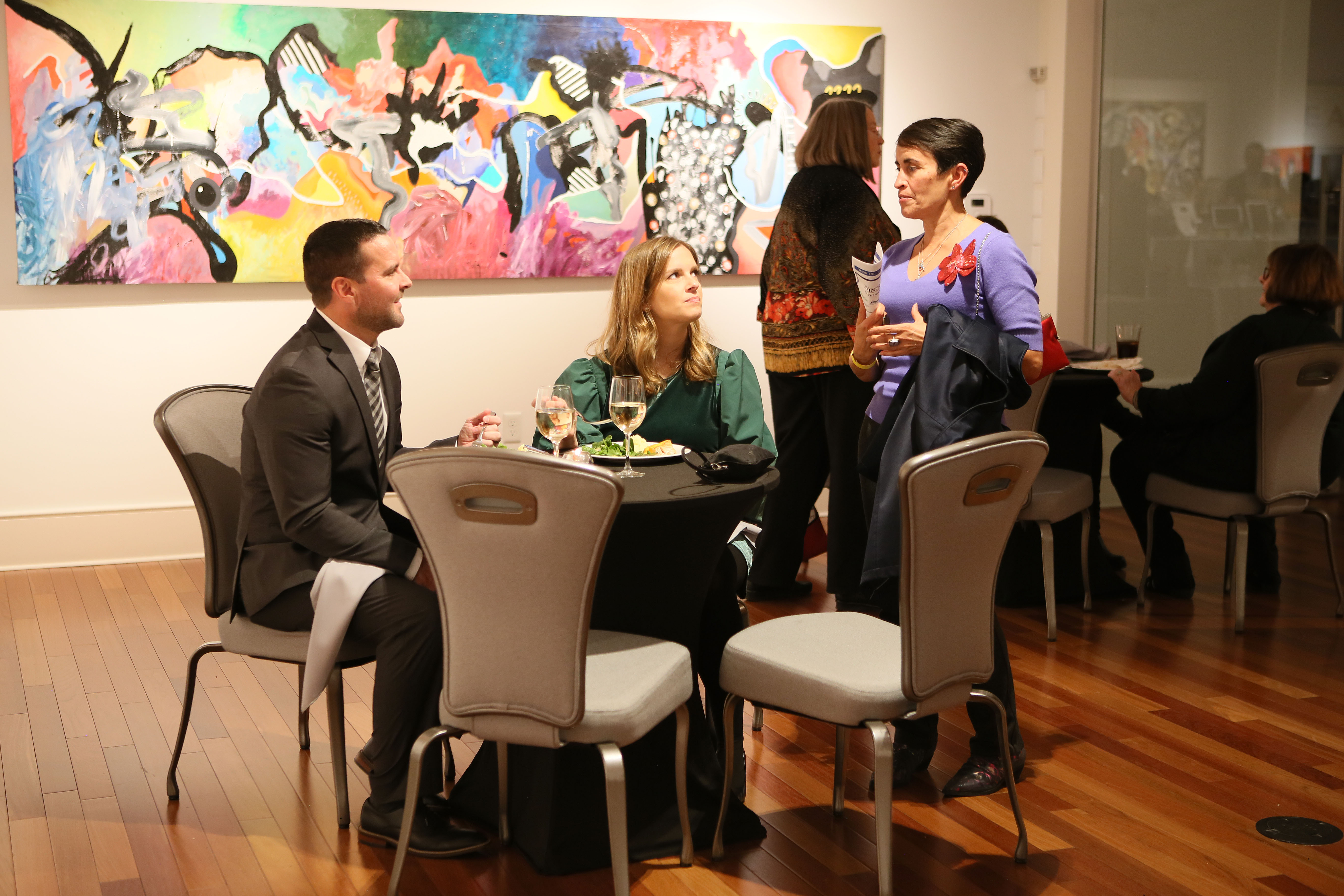 Guests enjoy meal and conversation in front of painting